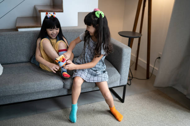 istock Happy sisters putting on colorful socks at home 1308829883