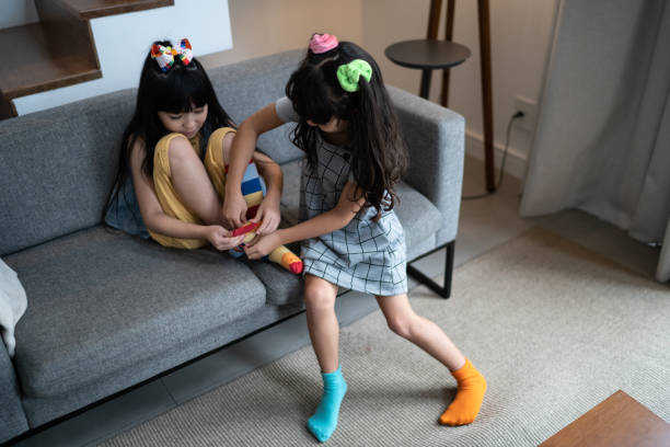 istock Happy sisters putting on colorful socks at home 1308829889
