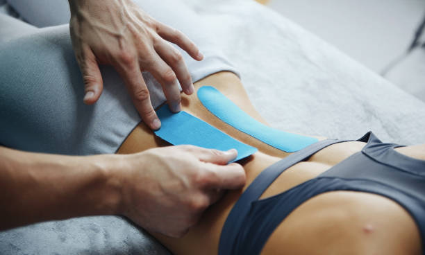 doctor helps woman by shoulder treatment with kinesio tape - kinesio imagens e fotografias de stock