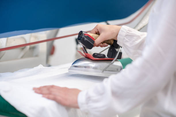 istock Female hands with iron over ironing board 1308832963
