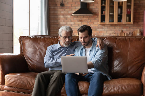 istock Grownup son and old father use laptop at home 1308834365