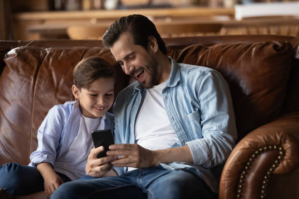 istock Smiling father and little son have fun using smartphone 1308834385