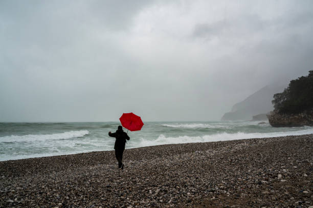 Lonely man walking on the beach on a rainy day