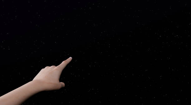 istock woman's hand pointing to starry sky 1308838360