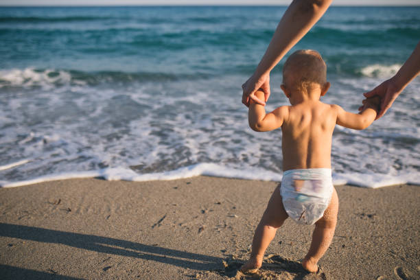 istock Mom helps to make the child's first steps on the beach 1308840235