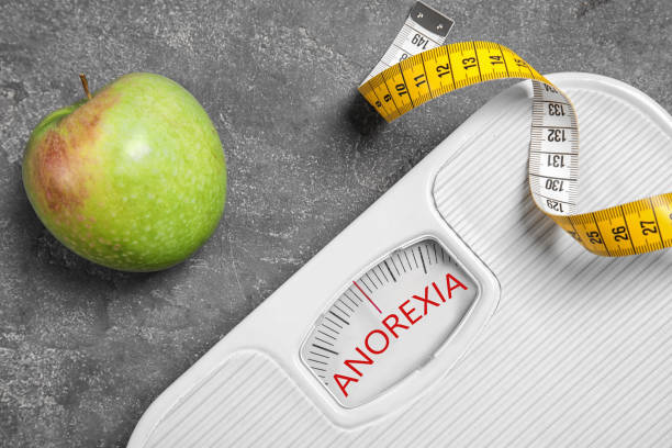 istock Anorexia concept. Scales, measuring tape and apple on grey background, flat lay 1308840577