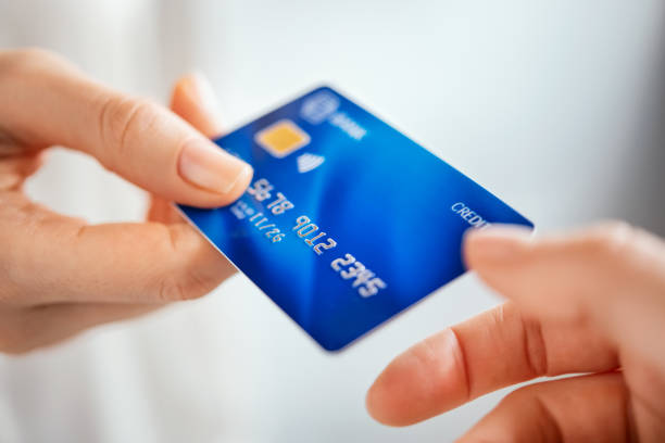 Woman hand passing credit card Close up shot of a woman passing a payment credit card to the seller. Woman hand giving credit card to cashier. Detail of girl giving bank creditcard for payment to waitress. passing giving stock pictures, royalty-free photos & images