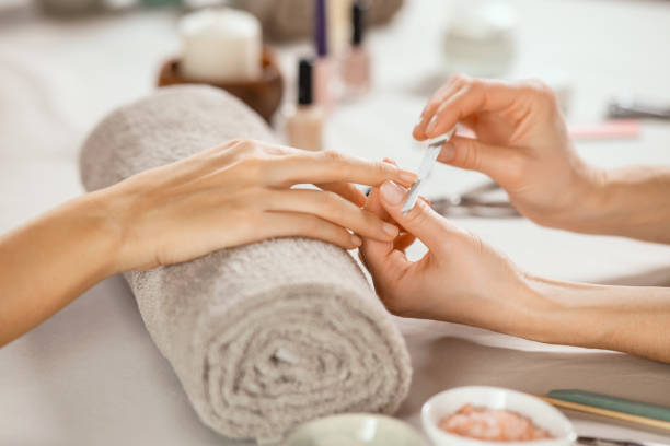 Woman doing manicure Close up shot of a woman in a nail salon receiving manicure by beautician with metal nail file. Woman getting nail manicure at spa centre. Beautician file nails to a customer in luxury salon. manicure stock pictures, royalty-free photos & images