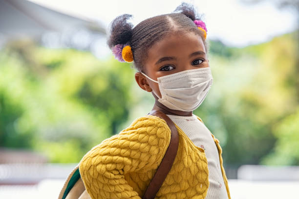 niña negra feliz con máscara facial lista para ir a la escuela primaria - coronavirus fotos fotografías e imágenes de stock