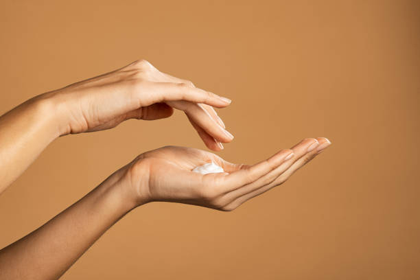 Woman hand applying lotion cream Close up shot of beautiful female hands holding and applying moisturiser. Beauty woman hand applying cream. Beautiful girl on creamy background holding moisturizer. suntan lotion stock pictures, royalty-free photos & images