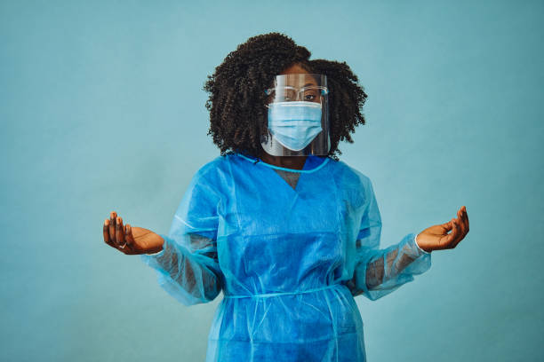 istock Nurse practitioner with personal protective equipment face shield goggles both hands out covid 19 1308844993