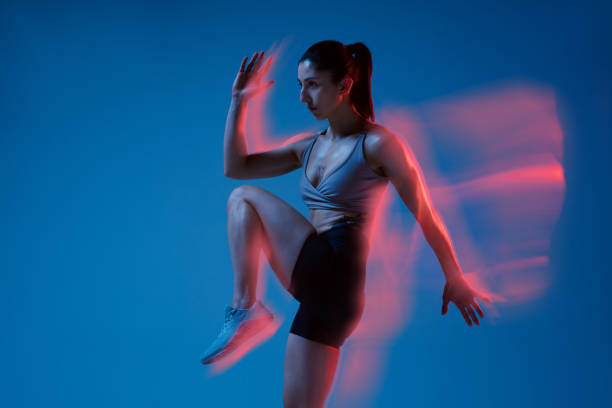 istock Caucasian professional female athlete training on blue studio background in neon, mixed light. Muscular, sportive woman. 1308846174