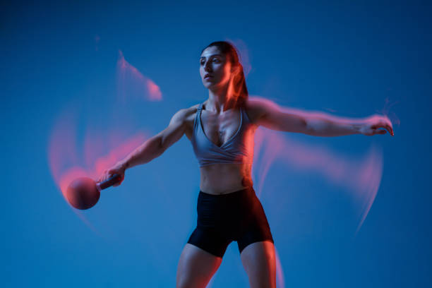 istock Caucasian professional female athlete training on blue studio background in neon, mixed light. Muscular, sportive woman. 1308846190