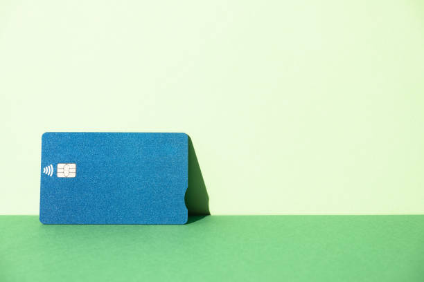 Blue credit card resting on a green background with a big copy space