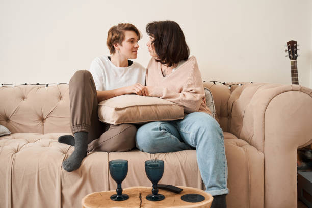 istock Lesbian couple hugging and looking at each other while sitting at the sofa 1308848816