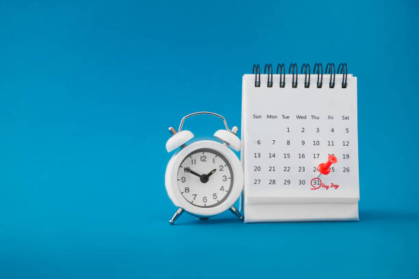 red thumbtack pin on the last day  of month with circle and pay day word near white analog clock on grunge blue background for business and finance concept - calendar calendar date reminder thumbtack imagens e fotografias de stock