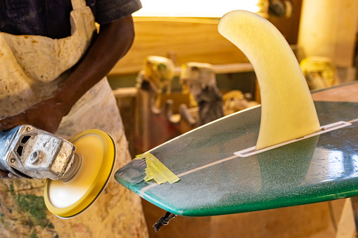 Close up of a African Craftsman surfboard Shaper working in a repair workshop