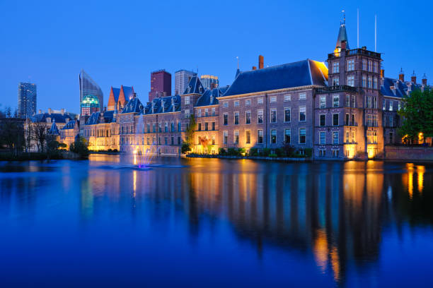 Hofvijver lake and Binnenhof , The Hague View of the Binnenhof House of Parliament and the Hofvijver lake with downtown skyscrapers in background illuminated in the evening. The Hague, Netherlands binnenhof photos stock pictures, royalty-free photos & images