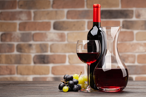 Wine decanter, bottle, glass of red wine and grapes. With copy space
