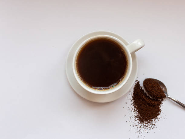 istock ground coffee on a spoon with a cup of black coffee on a white background 1308857833