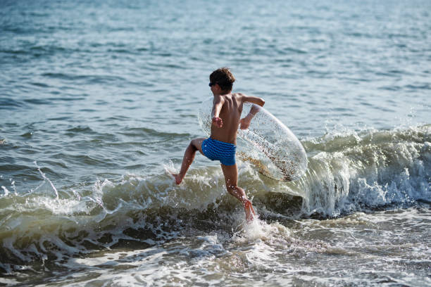 istock Little boy playing in sea waves 1308859844