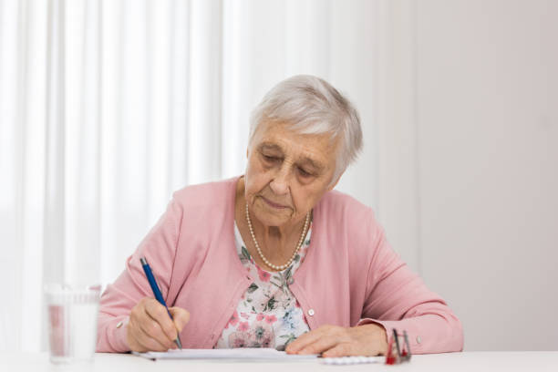 istock Elderly woman signs a document 1308860868