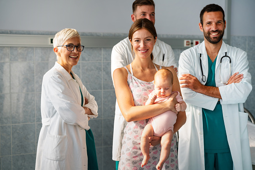 Portrait of happy mother with baby, medical pediatrician doctors, nurse. Health care, people, insurance concept