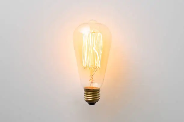 Photo of vintage light bulb glows without wires on white background