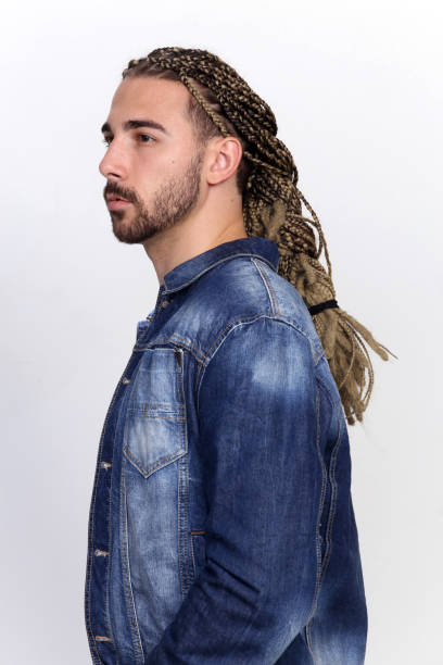 istock Attractive blonde male model with combination of braids and dreadlocks posing in studio on isolated background. 1308863535