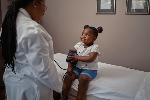 Shot of a doctor checking an adorable little girls blood pressure in her consulting room