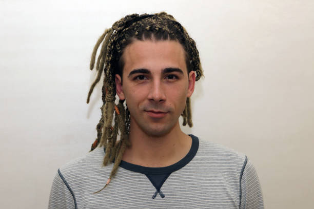istock Attractive blonde male model with combination of braids and dreadlocks posing in studio on isolated background. 1308869679