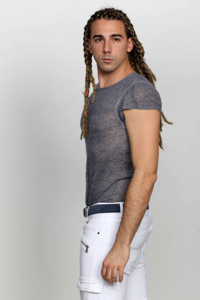 istock Attractive blonde male model with combination of braids and dreadlocks posing in studio on isolated background. 1308870081