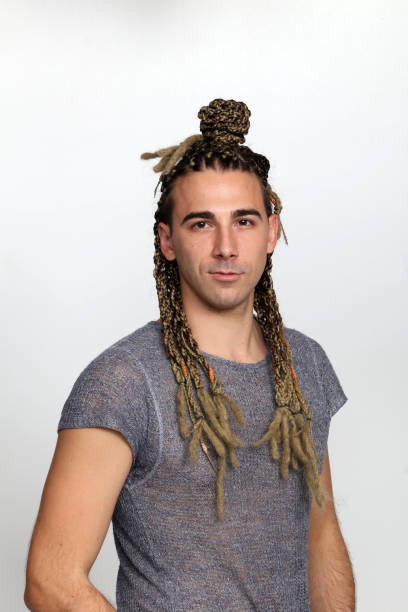 istock Attractive blonde male model with combination of braids and dreadlocks posing in studio on isolated background. 1308870088