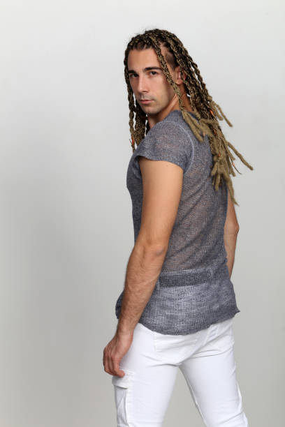 istock Attractive blonde male model with combination of braids and dreadlocks posing in studio on isolated background. 1308870103