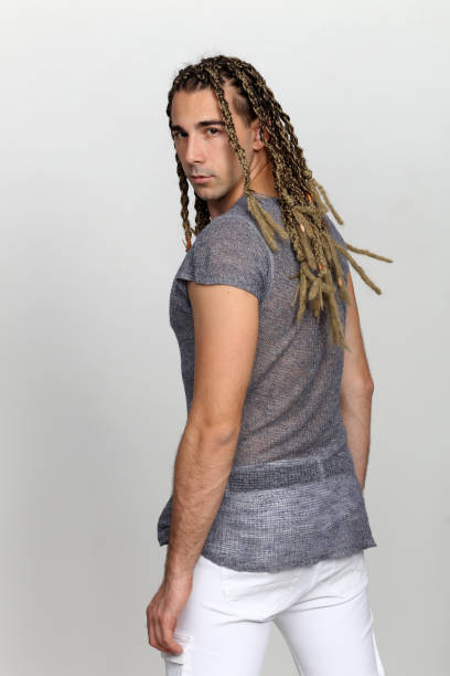 istock Attractive blonde male model with combination of braids and dreadlocks posing in studio on isolated background. 1308870124