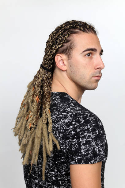 istock Attractive blonde male model with combination of braids and dreadlocks posing in studio on isolated background. 1308870167