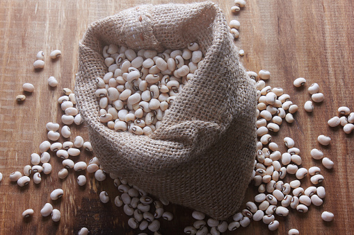 Raw grains fradinho beans in rustic bag on wooden table. top view
