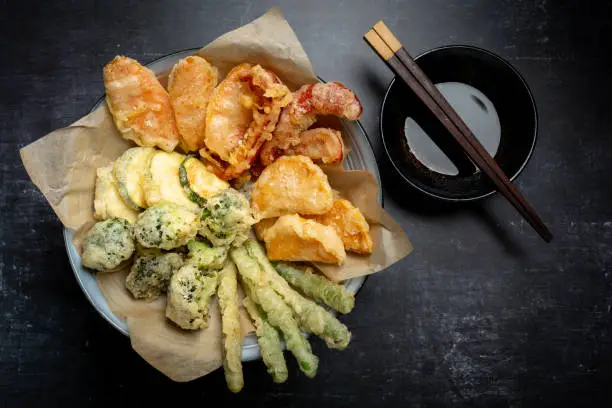 Horizontal flat lay of Japanese vegetable tempura recipe with ginger ponzu sauce , black background with copy space