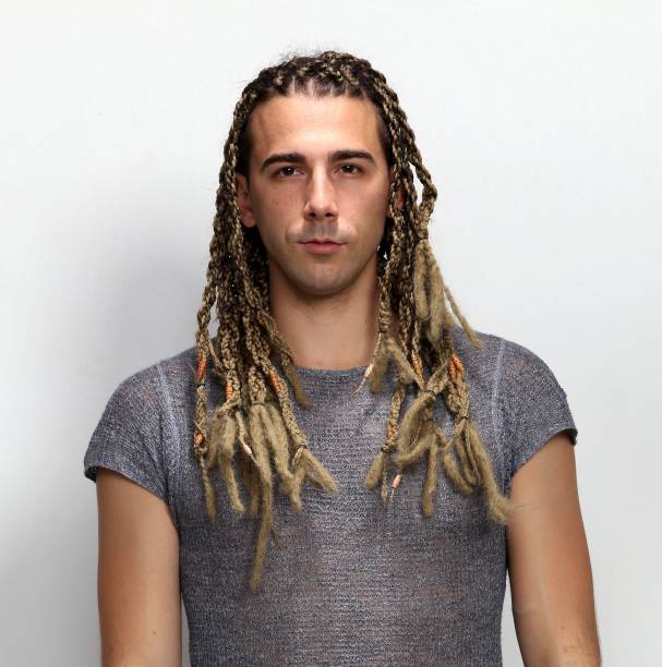 istock Attractive blonde male model with combination of braids and dreadlocks posing in studio on isolated background. 1308872029