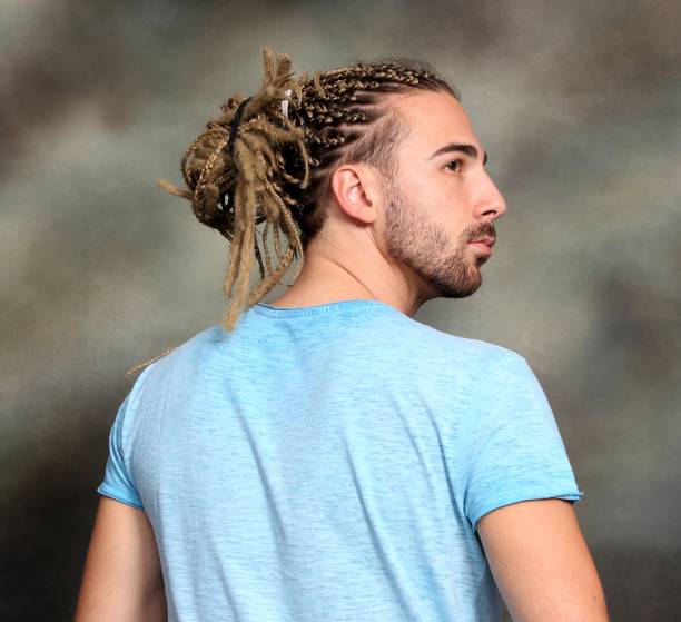 attraktive blonde männliche modell mit kombination von zöpfen und dreadlocks posiert im studio auf isolierten hintergrund. - young men men blond hair attractive male stock-fotos und bilder