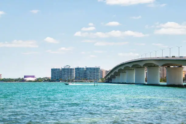 Beach in city of Sarasota, Florida on sunny day with cityscape and bay buildings by John Ringling causeway bridge in summer