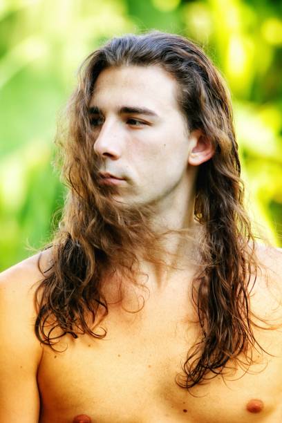 istock Attractive guy with very long hair is posing in the wild. 1308874672