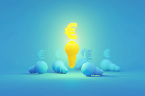 Yellow Euro symbol sitting above a glowing yellow light bulb surrounded by blue lightbulbs over blue background. Horizontal composition with copy space. Creativity, innovation, new business and business idea concept.