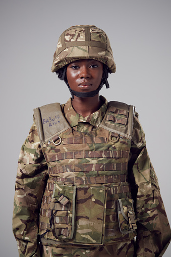 Retrato de estudio de una joven soldado seria con uniforme militar contra antecedentes llanos photo