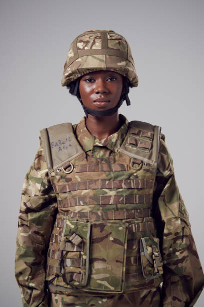 Studio Portrait Of Serious Young Female Soldier In Military Uniform Against Plain Background Studio Portrait Of Serious Young Female Soldier In Military Uniform Against Plain Background military uniform stock pictures, royalty-free photos & images