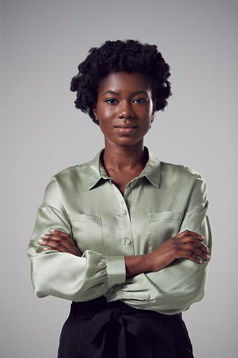 Studio Portrait Of Serious Young Businesswoman With Folded Arms Against Plain Background
