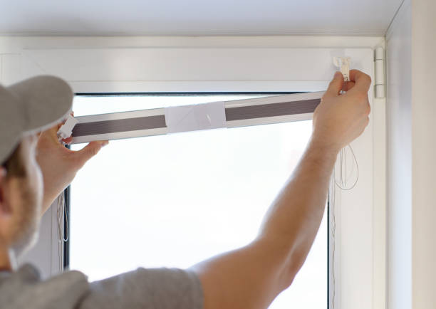 istock Man installing gray pleated blinds on the window with screwdriver 1308887932