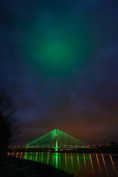Photo of Modern line bridge illuminated with green lights for St. PAtricK in Waterford Ireland. Overnight.