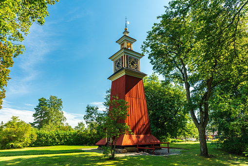 Beautiful summer view of a red wooden clock tower, standing at a closed down silver mine in Sweden