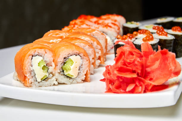 istock Rolls with salmon and cucumber, cheese and wasabi on a white plate. Closeup, selective focus 1308890356
